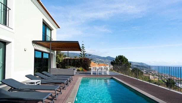 A swimming pool with lounge chairs, a pergola, and a view of the sea and mountains. - Villa Eden Nature in Prazeres (Calheta)