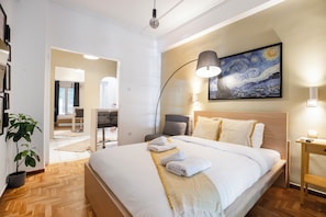 A modern hotel room with a large bed, a painting on the wall, and a lamp.