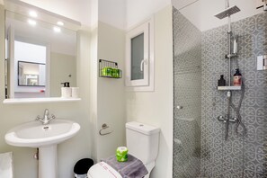 A bathroom with a white sink, a toilet, a shower with a glass enclosure, and a mirror above the sink.