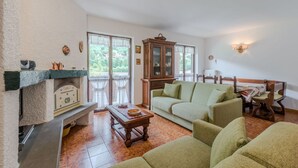 A cozy living room with a fireplace, a sofa set, a wooden cabinet, and a dining table.