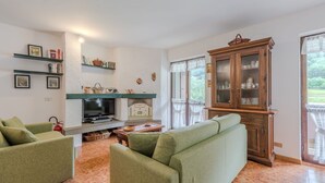A living room with green sofas, a wooden cabinet, a fireplace, and a television.