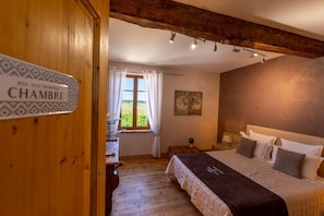 Une chambre à coucher avec un lit, un plancher en bois, une fenêtre avec des rideaux, un tableau au mur et une pancarte sur la porte.