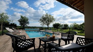 Un espace aménagé au bord de la piscine, avec des chaises longues, une table où sont servis des boissons, et une vue sur la piscine et les environs.