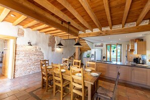 A rustic kitchen with wooden beams, a brick wall, and a dining area with wooden chairs and a table. - Le Mazage des Trégans - Heated Pool - Park (Gaillac)