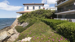 A coastal building with a white facade and arched windows, adjacent to a modern building with balconies. - Cosy apartment for 7 guests with WIFI, TV, terrace and pets allowed (Civitavecchia)