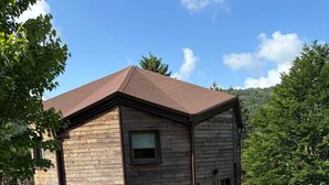 Una casa moderna de dos pisos con fachada de piedra, un garaje frontal y un camino de entrada ajardinado.