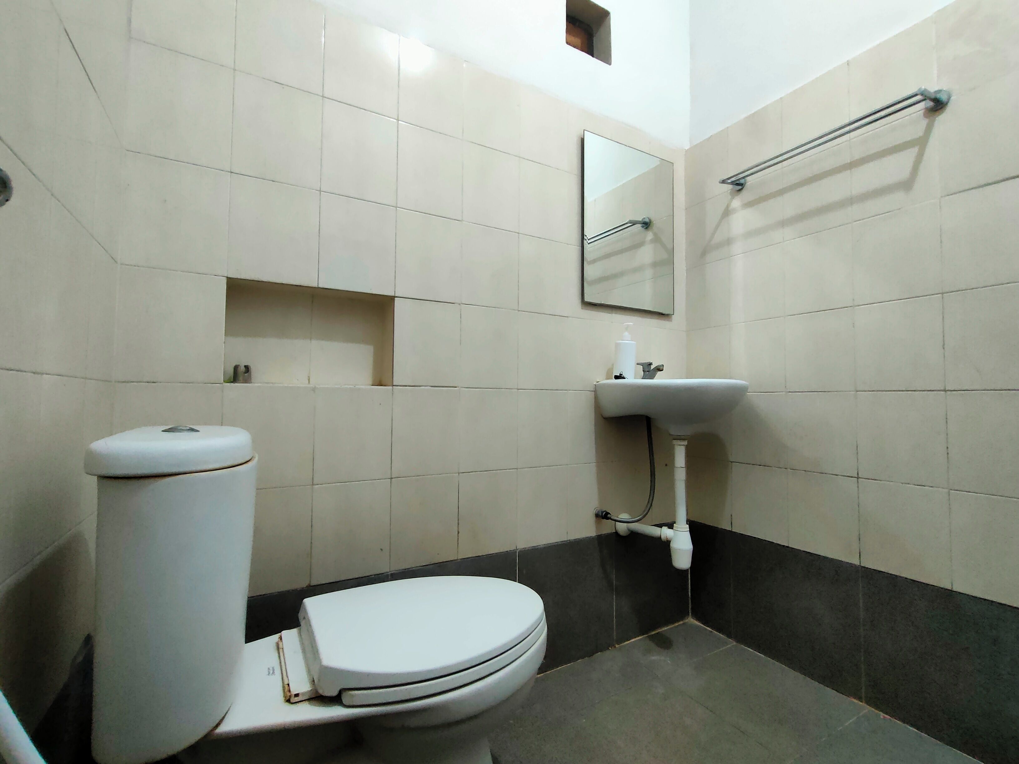 A bathroom with a toilet, sink, and mirror.