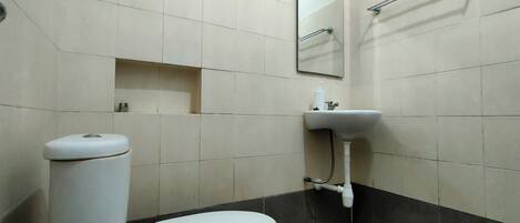A bathroom with a toilet, sink, and mirror.