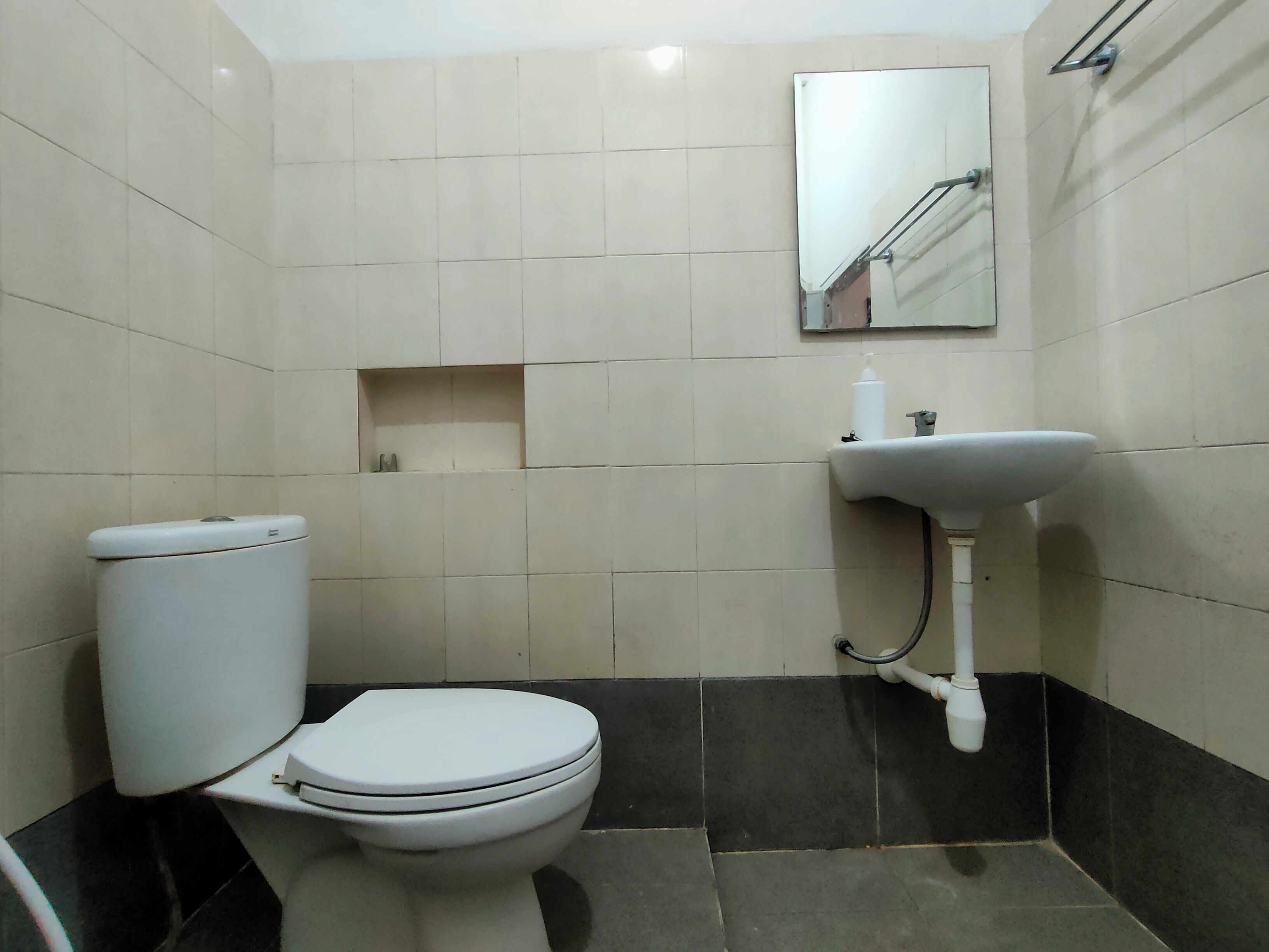 A small bathroom with a toilet, sink, and mirror.