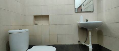 A small bathroom with a toilet, sink, and mirror.