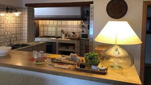A kitchen with a wooden countertop, a sink, a stove, and a wall clock.