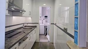 A modern kitchen with white cabinets, a granite countertop, and a built-in stove. - Spectacular beachfront. 3 bedrooms very central. (Almuñécar)