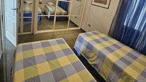 A room with two beds, a wardrobe, a ceiling fan, and a painting on the wall. - Spectacular beachfront. 3 bedrooms very central. (Almuñécar)