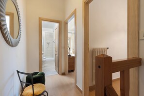 A hallway with a wooden chair, a mirror, and a radiator.