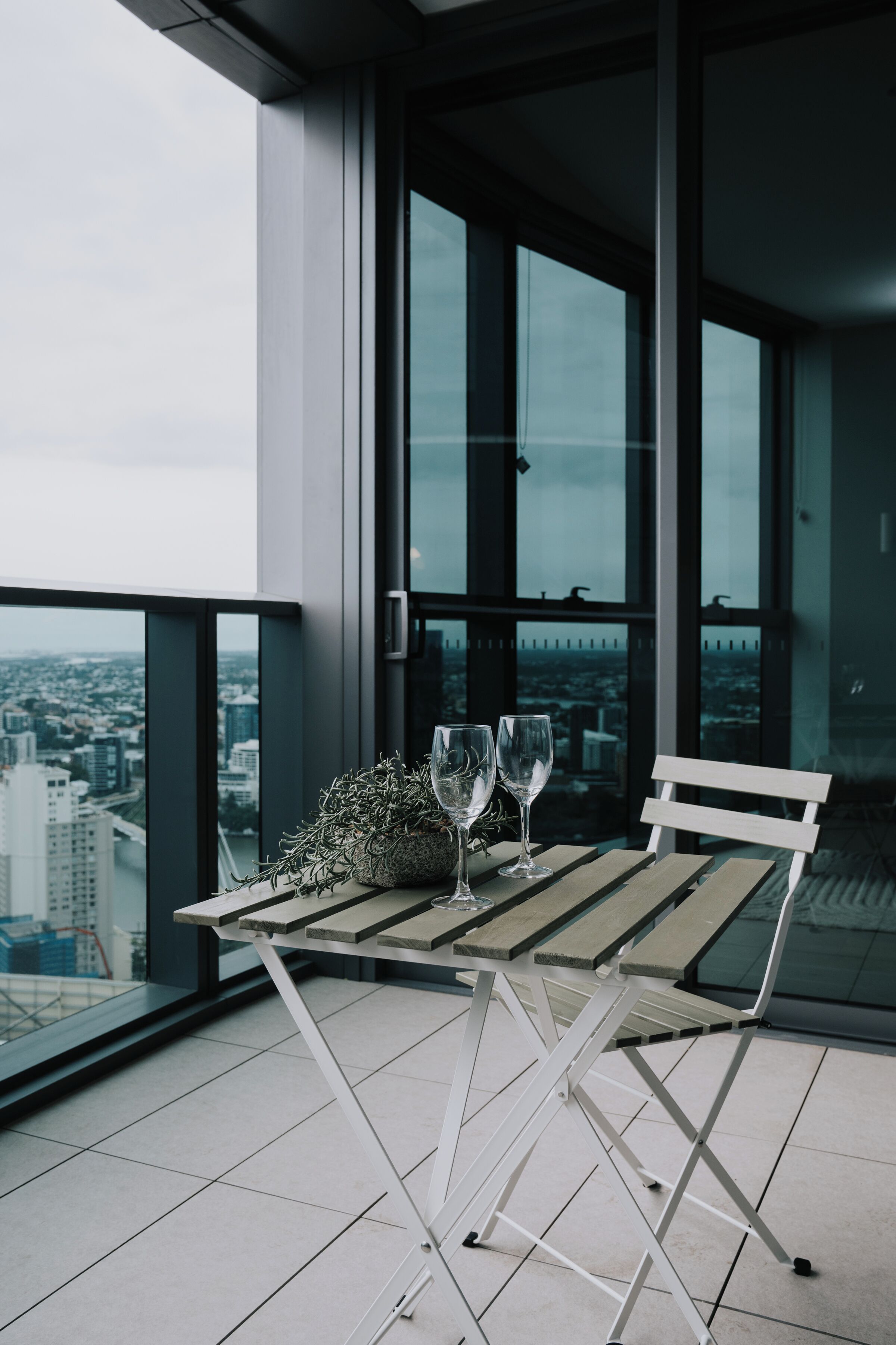 Ein Balkon mit Tisch, zwei Gläsern und einer Sitzbank.