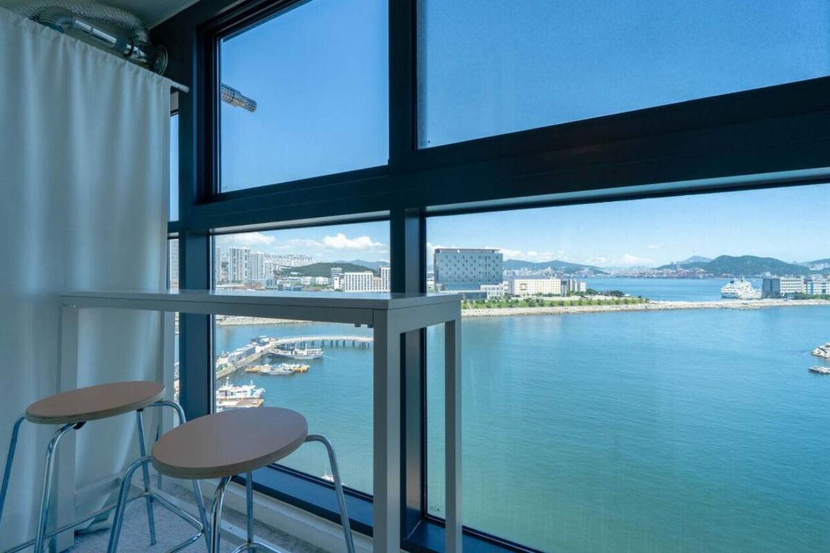A room with a large window overlooking a marina and cityscape.