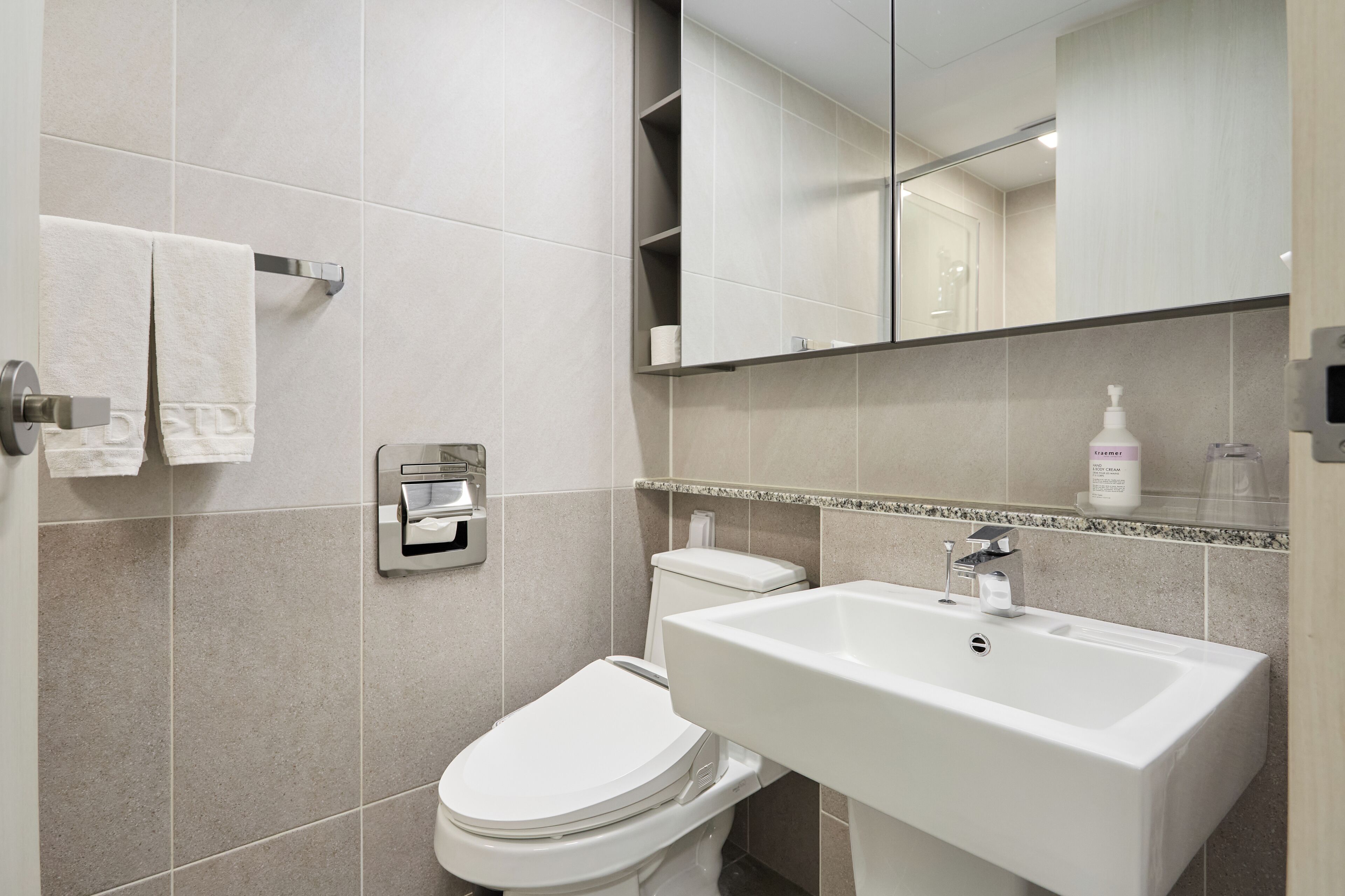 A modern bathroom with a toilet, sink, and towel rack.