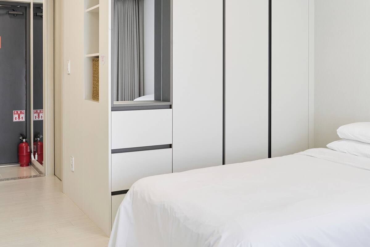 A modern bedroom with a bed, a wardrobe, and a mirror.