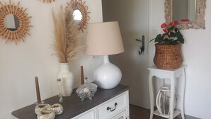 A white cabinet with decorative items, a lamp, and a mirror on the wall. - Lovely 3-bedroom family home for rent Ideal location (La Rochelle)