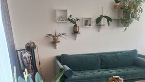 A living room with a teal sofa, a round coffee table, and various potted plants. - Lovely 3-bedroom family home for rent Ideal location (La Rochelle)