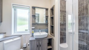 Moderni kylpyhuone, jossa on wc, pesuallas ja suihku.