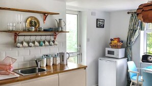 Una cocina compacta con encimera de madera, un fregadero y un refrigerador blanco. Se observa una ventana con vistas a zonas verdes.