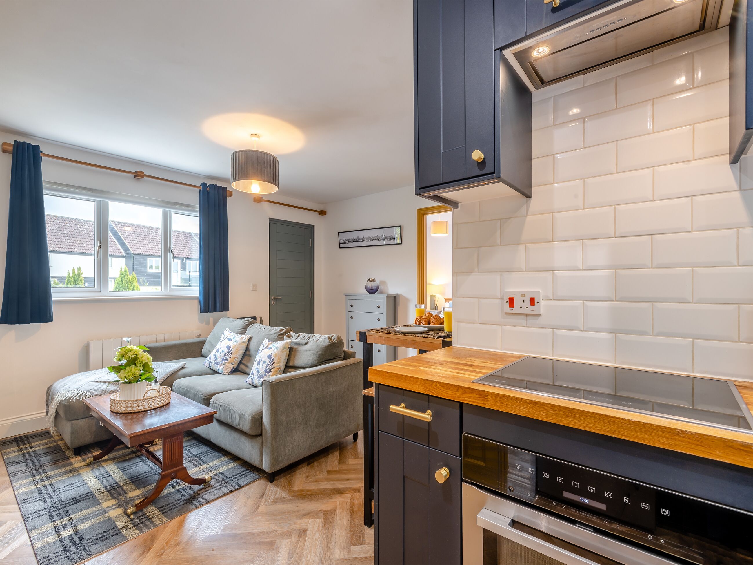 Eine moderne Küche mit Backofen, ein Essbereich mit einer Couch und ein Fenster mit Vorhängen.