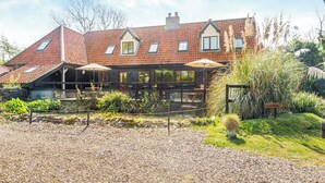 A two-story building with a red-tiled roof, a gravel driveway, and a guest parking sign. - 7 bedroom accommodation in Ilketshall St Margaret near Bungay (Ilketshall St Margaret near Bungay)