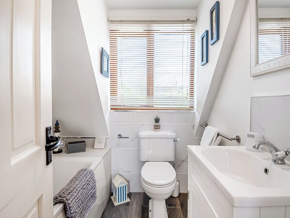A compact, modern bathroom with a toilet, sink, and bathtub.