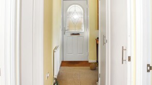 A narrow hallway with a white door featuring a frosted glass panel.