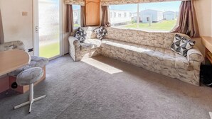 A cozy room with a stone-patterned sofa, a wooden cabinet, and a dining table.