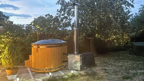 A wooden hot tub with a metal chimney, surrounded by potted plants and a stone pathway. - 2 bedroom accommodation in Winestead (Winestead)
