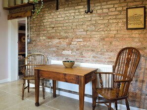 A dining area with a brick wall, wooden table, and two chairs.