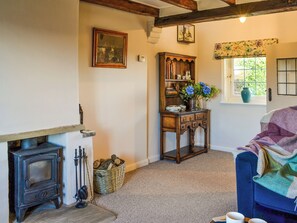 A cozy room with a vintage stove, a wooden cabinet with decorative items, and a window with a view of greenery.