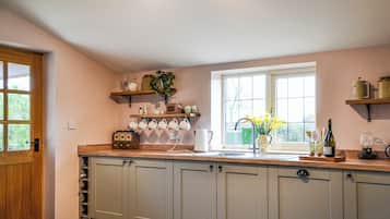 Une cuisine avec une porte en bois, une fenêtre donnant sur un beau paysage et un plan de travail sur lequel sont disposés divers objets.