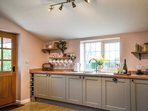 A kitchen with a wooden door, a window with a view, and a countertop with various items.