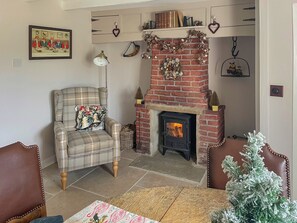 Un salon chaleureux avec une cheminée, un fauteuil à carreaux et un sapin de Noël.