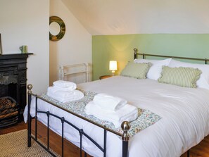 A neatly made bed with white linens and pillows, a bedside lamp, and a decorative mirror on the wall.