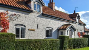 A white brick cottage with a red-tiled roof, a small attached garage, and a well-maintained hedge. - 2 bedroom accommodation in Winestead (Winestead)