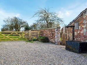 A gravel driveway leading to a brick building with a wooden gate.