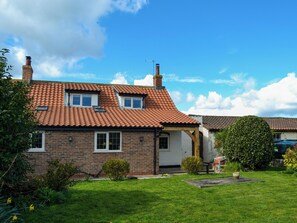 A two-story house with a red-tiled roof, brick walls, and a small front garden.