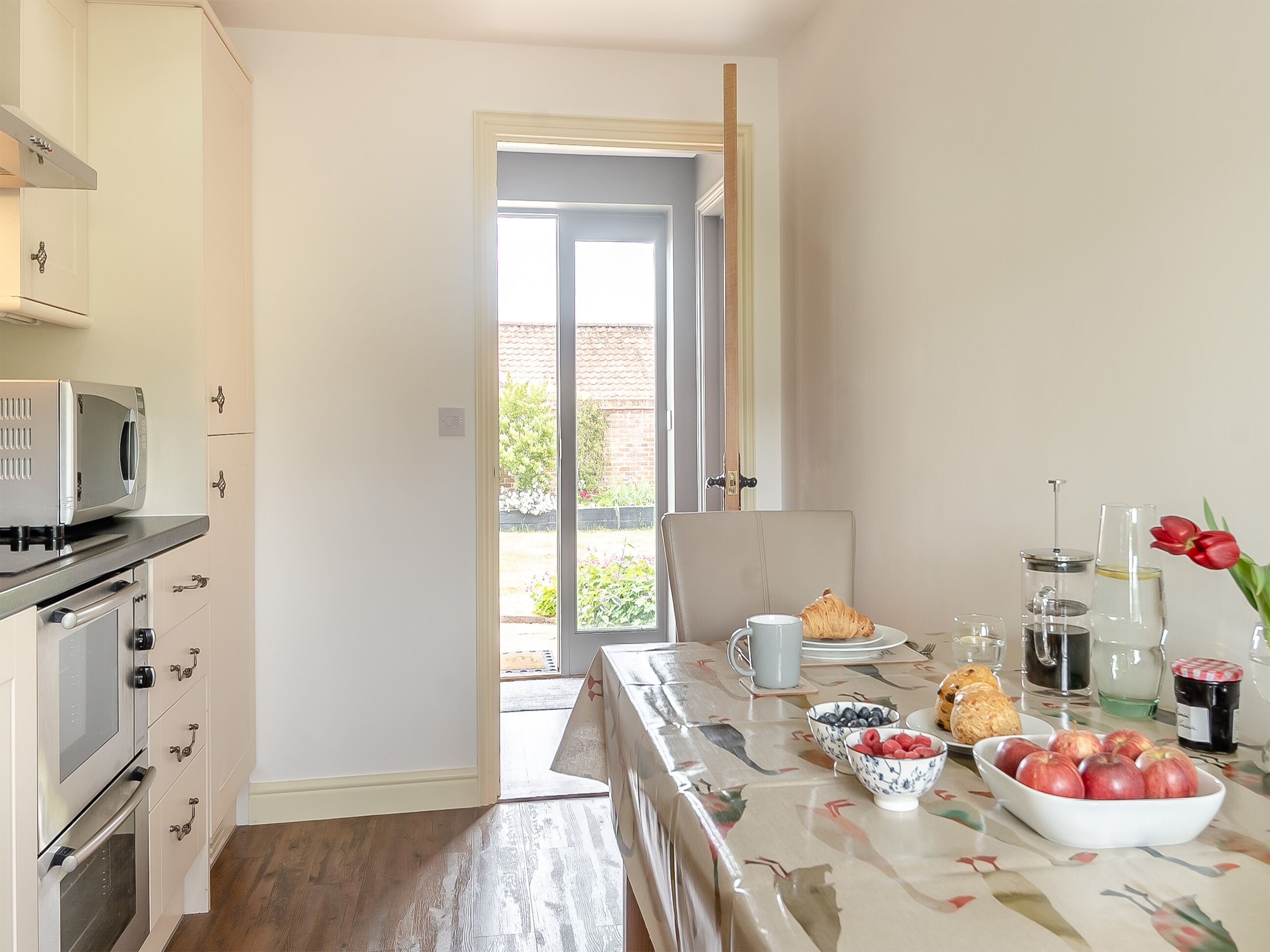 Una cocina equipada con microondas y horno, y un comedor con mesa dispuesta para el desayuno.