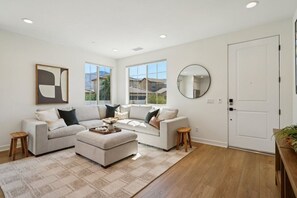 A modern living room with a sectional sofa, a coffee table, and a large window offering a view of the outside.