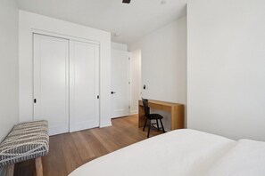 Ein Schlafzimmer mit einem Bett, einem Schreibtisch und einem Stuhl. Es gibt einen Kleiderschrank und eine Bank.