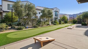A residential area with a well-maintained lawn, a wooden board game, and a house with a tiled roof. - Heated Pool Oasis by the Santa Rosa Mountains (La Quinta)