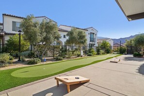 A residential area with a well-maintained lawn, a wooden board game, and a house with a tiled roof. - Heated Pool Oasis by the Santa Rosa Mountains (La Quinta)