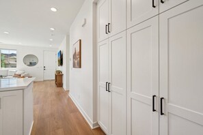 Una cocina moderna con armarios blancos, piso de madera y un espejo redondo en la pared.