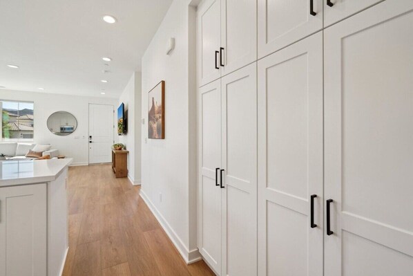 A modern kitchen with white cabinetry, a wooden floor, and a round mirror on the wall.
