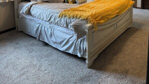 Un dormitorio con cama, ventilador de techo, ventana con cortinas y un armario de madera.