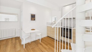 A modern kitchen with white cabinetry, a wooden countertop, and a white staircase. - Host Stay The Surf Shack (Saltburn-by-the-Sea)